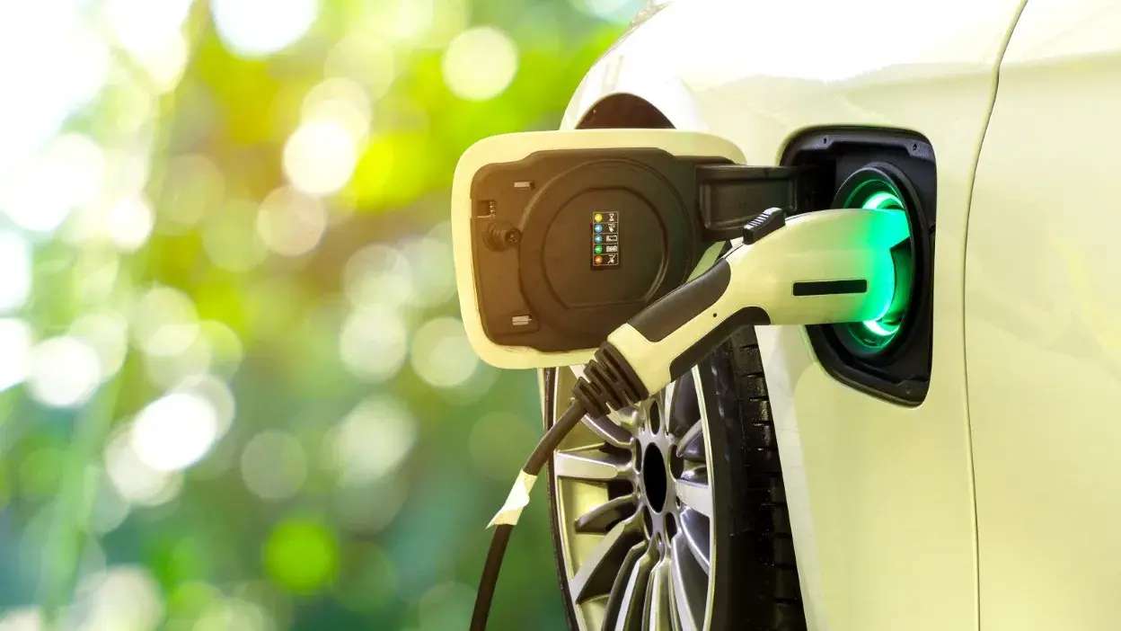 Cabo de carregamento ligado a carro elétrico branco com luz verde no encaixe de carga