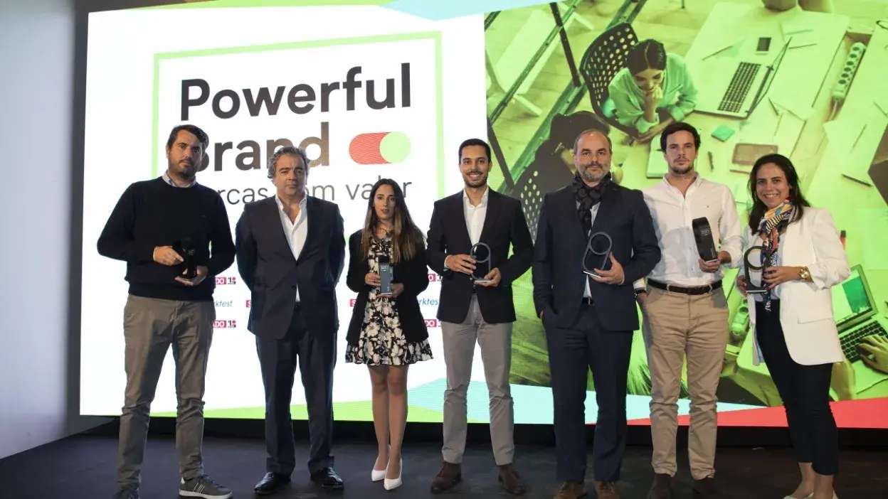 Grupo de sete pessoas em palco a segurar troféus do prémio Powerful Brand.