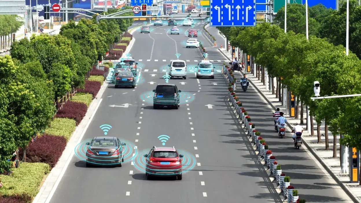 Vários carros numa estrada com sinais gráficos a indicar comunicação entre veículos autónomos.