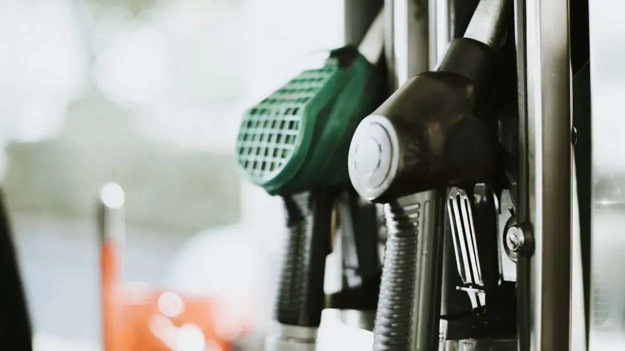 Bicos de abastecimento numa bomba de combustível, um verde e outro preto.