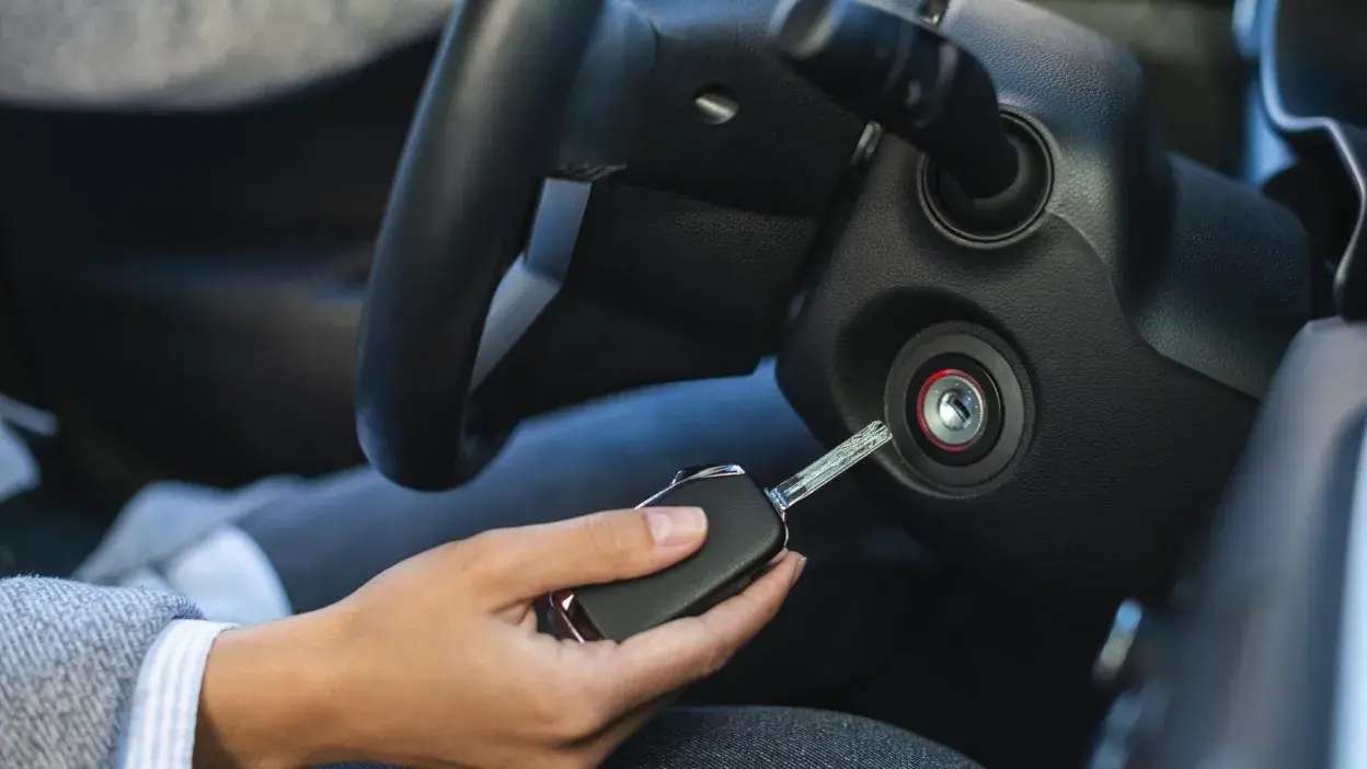Mão a inserir chave na ignição de um carro.