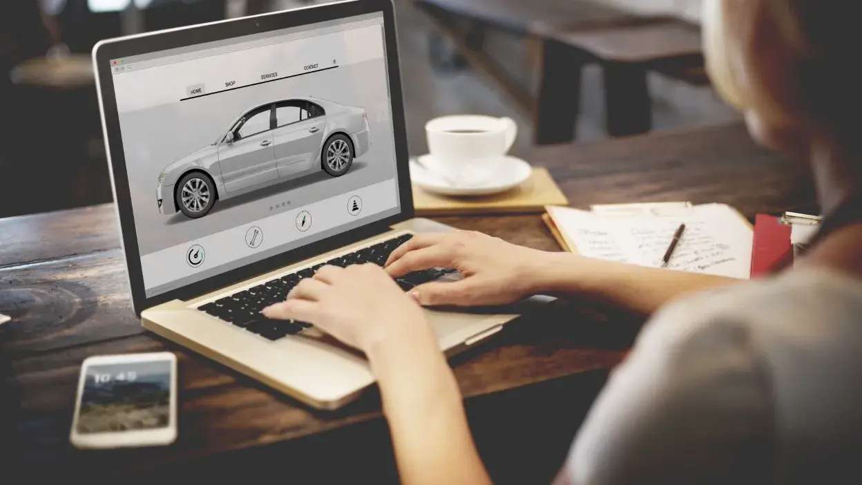 Pessoa a usar computador para consultar informações sobre um carro num website.
