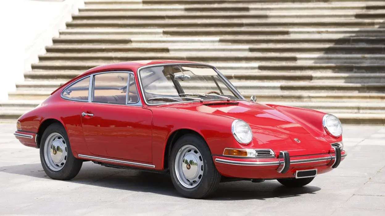 Automóvel clássico vermelho estacionado em frente a escadaria exterior.