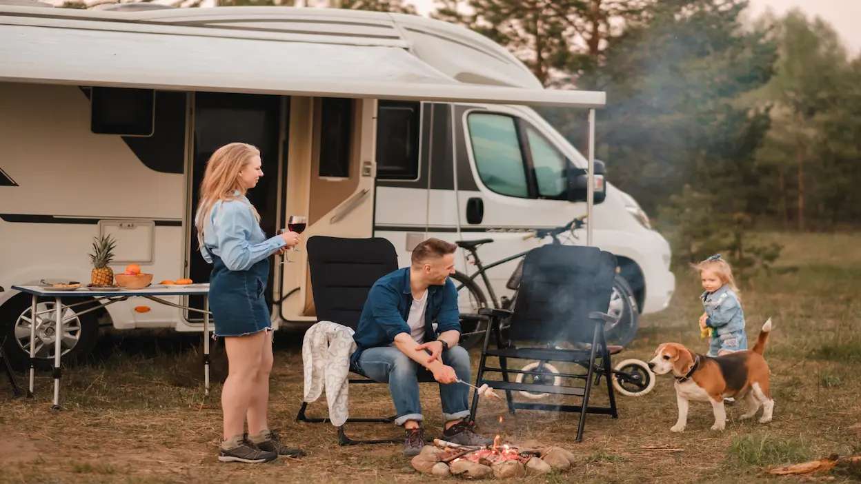 Familia a fazer um churrasco em frente a uma autocaravana