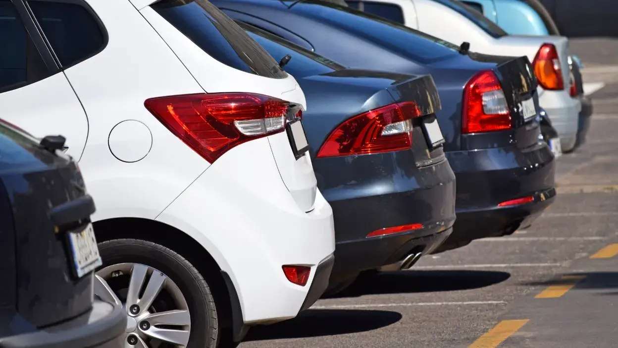 Vista traseira de vários carros estacionados lado a lado num parque de estacionamento ao ar livre