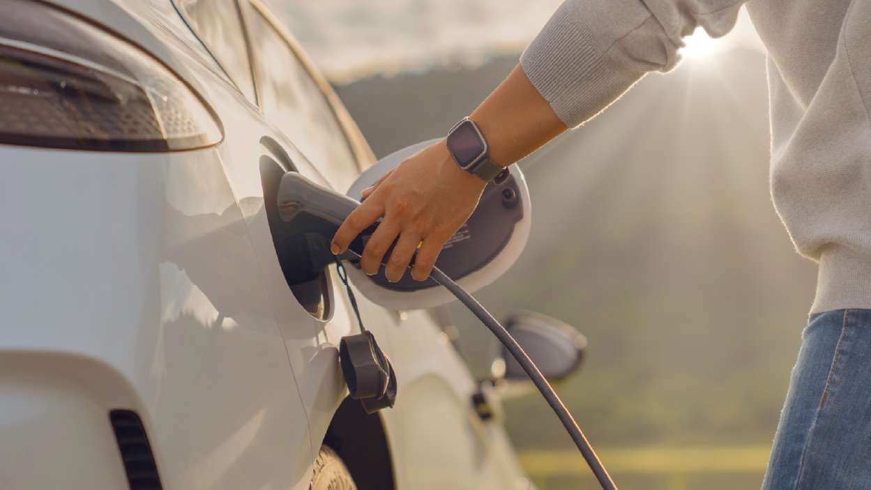 homem a carregar o seu carro elétrico num posto de carregamento da rua
